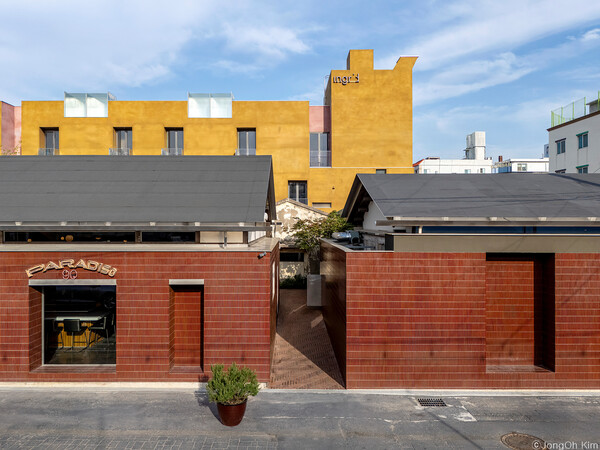 프로젝트 리터닝 군산의 상징적인 입면. 적갈색 타일을 두른 서쪽 진입로로 들어가면 적산가옥과 조적조, 신축이  뒤섞여 있는 제 3의 공간을 만난다. 뒤로 보이는 겨자색 건물이 신축 호텔 .(사진 김종오/ 이손건축 건축사사무소 제공)